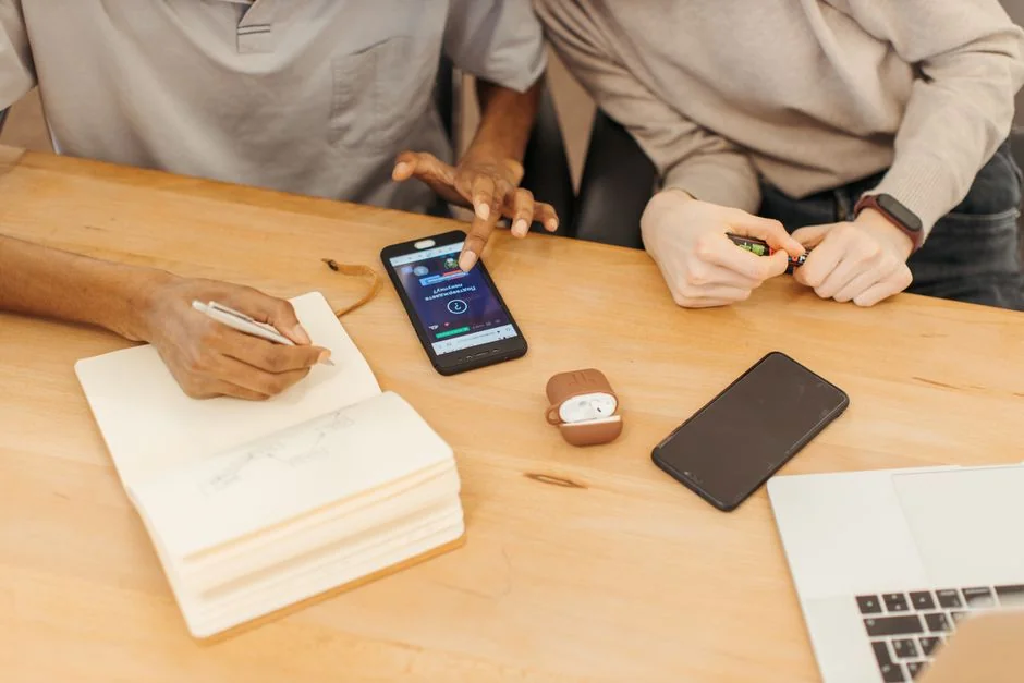 A hand holds a smartphone with the email app open, surrounded by books and a laptop.