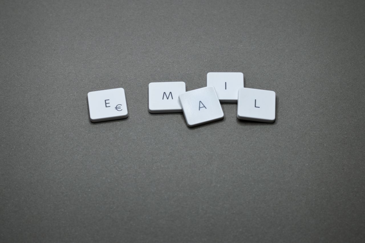 Close-up of the word email formed with letter tiles on a gray surface.